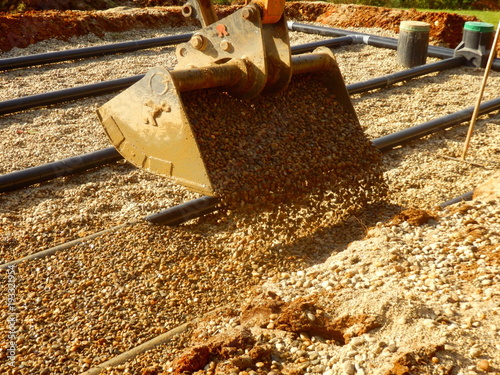 Gravel being poured onto the top layer of pipework, after the membrane and sand had been applied, during the construction of a sand and gravel drainage system photo