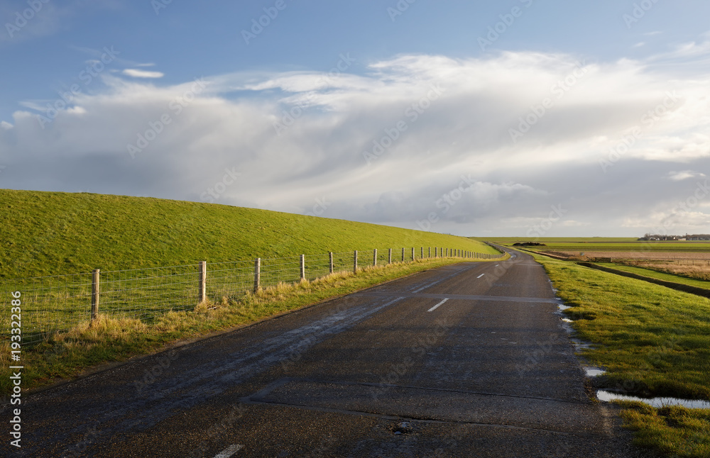 road between green hills and blue sky
