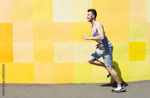 Side view of man running against bright wall