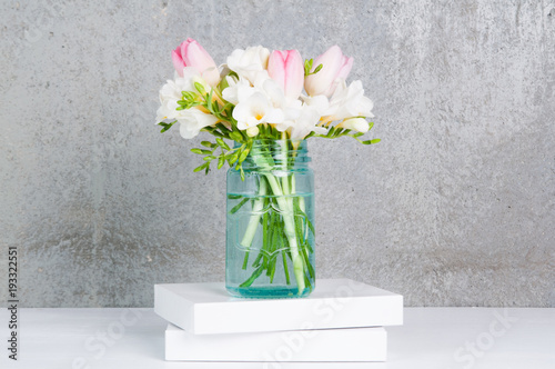 Fototapeta Naklejka Na Ścianę i Meble -  fressia and tulip flowers in a blue glass jar