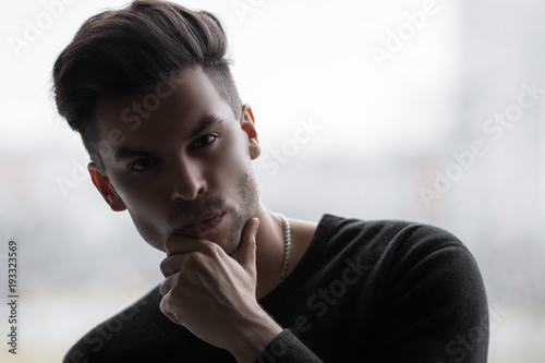 Photos The man holds a hand on his chin, in a pensive posture and cunning eyes