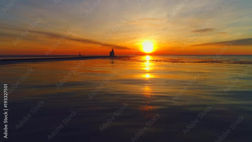Dramatic sunrise with scenic Lighthouse and flying Canadian Geese, reflected in calm water surface. Dramatic sunrise with scenic Lighthouse and flying Canadian Geese, reflected in calm water surface.