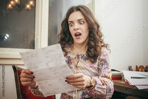 Quadro su tela Shocked young woman can't believe the amount of money on her electricity, cable