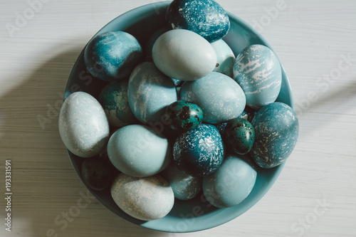 Naturally dyed Easter blue eggs, scattered on blue plate, on white wooden board photo