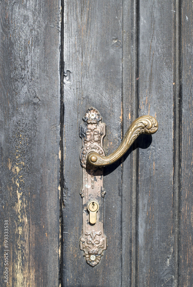 Obraz premium Old door handle on wooden closed door