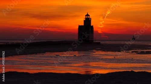 Winter twilight to sunrise time lapse of Kewaunee, Wisconsin lighthouse and Lake Michigan waters with dramatic red sky. photo