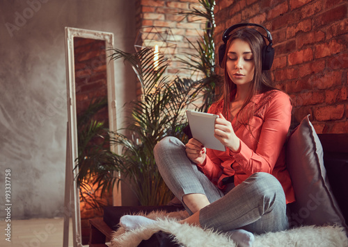 A charming brunette in casual clothes with a tablet and headphon photo