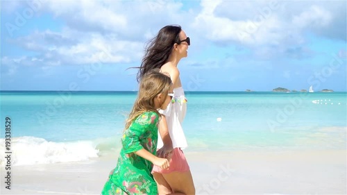 Beautiful mother and daughter on Caribbean beach. Family walking on tropical seashore