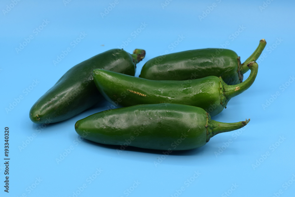 Fresh green jalapeno peppers arranged on a blue background. Fresh green jalapeno peppers arranged on a blue background.