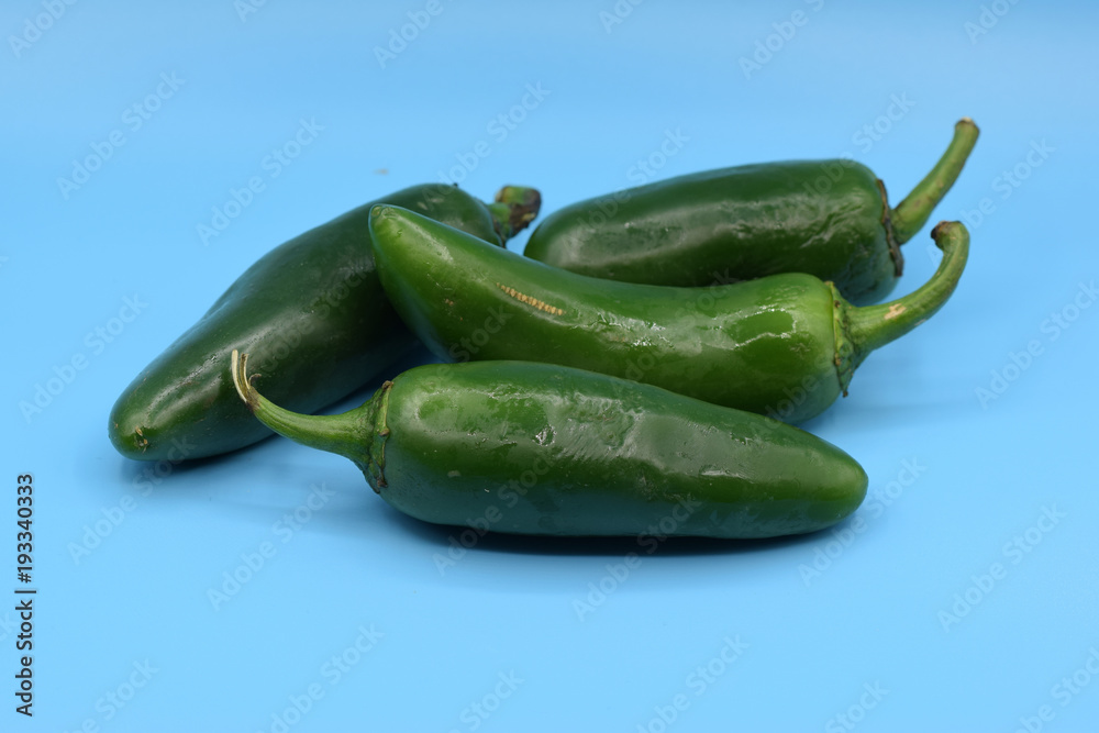 Fresh green jalapeno peppers arranged on a blue background. Fresh green jalapeno peppers arranged on a blue background.