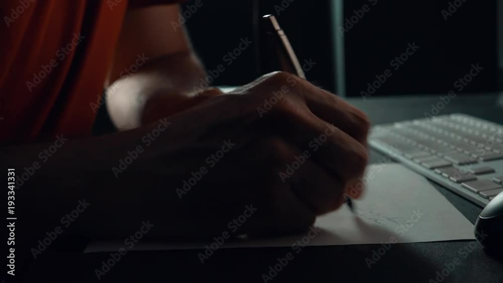 Close up of male hand writing notes in office t night, low key footage