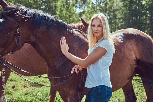 A charming woman standing with a brown horse.
