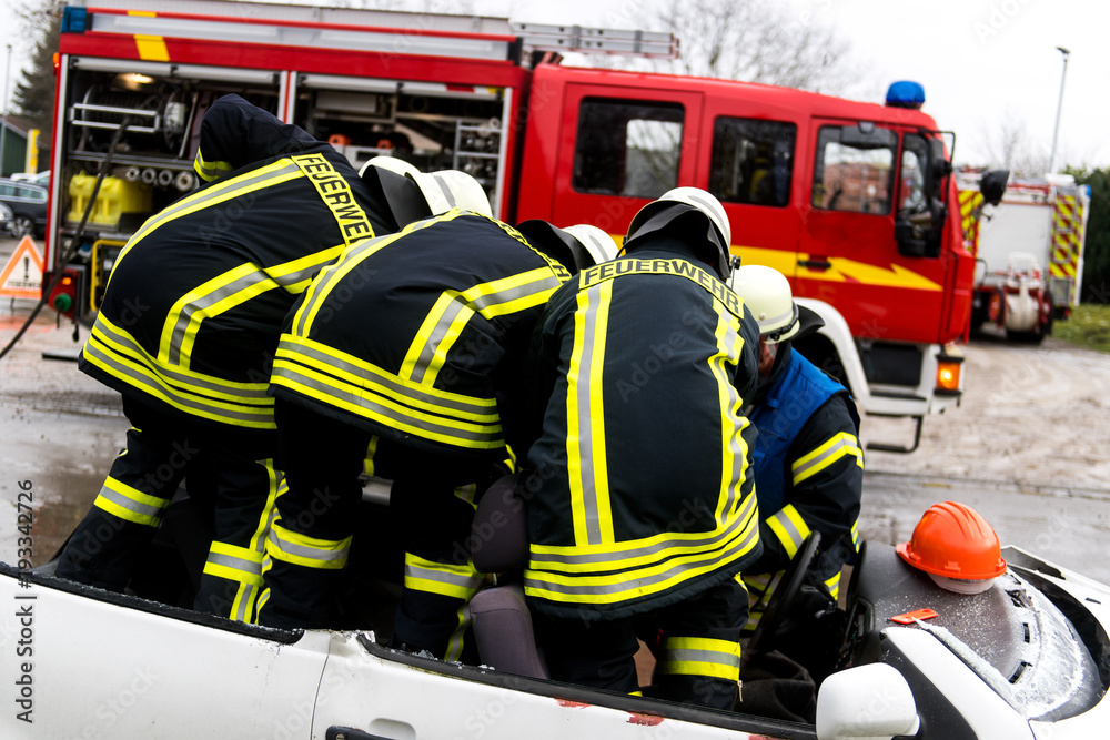 Naklejka premium Feuerwehrmänner befreien ein Unfallopfer nach einem Verkehrsunfall aus einem kaputten Auto