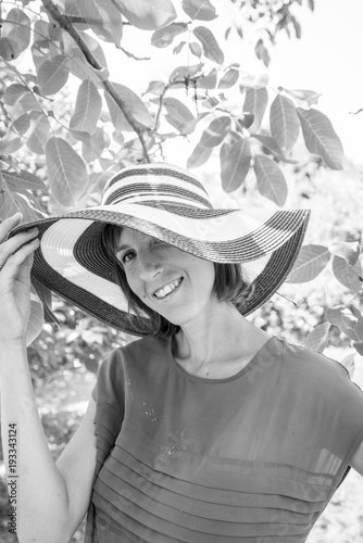 Monochrome portrait of a woman in a wide brimmed sunhat looking to the camera with a smile