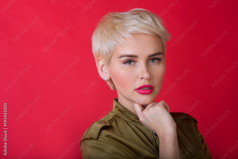 beautiful stylish young girl with a short hairstyle on a red background with a serious facial expression beautiful stylish young girl with a short hairstyle on a red background with a serious facial expression