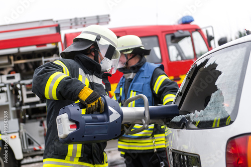 Feuerwehrmänner schneiden mit einer Rettungsschere ein Fahrzeug auf