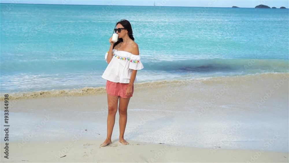 Young woman with hot coffee on white tropical beach. SLOW MOTION Young woman with hot coffee on white tropical beach. SLOW MOTION