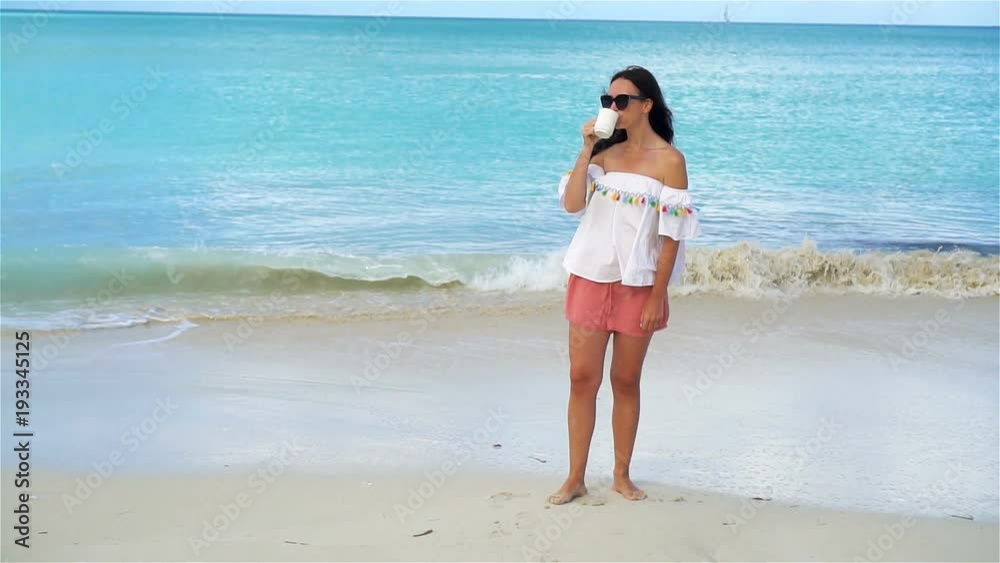 Young woman with hot coffee on white tropical beach. SLOW MOTION Young woman with hot coffee on white tropical beach. SLOW MOTION