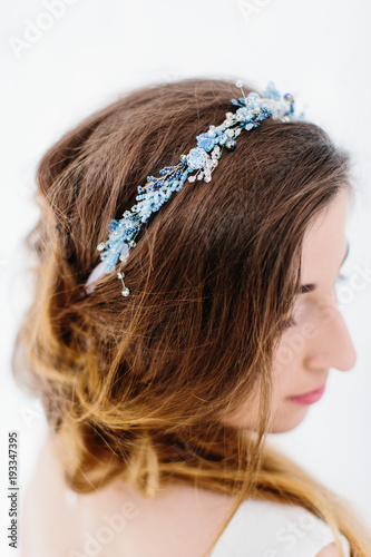 Young beautiful bride with a beautiful diadem in the hair poses standing on white background.