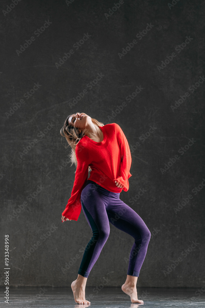 Young beautiful female dancer is posing in the studio