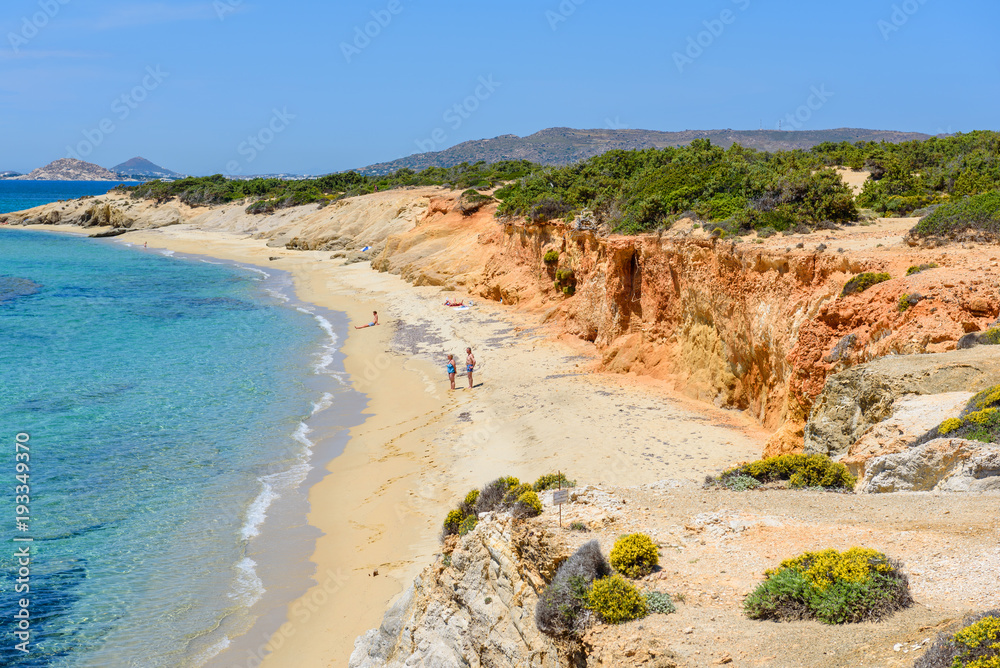 Tourists sunbathing on Aliko beach, one of the best beaches on the south western side of Naxos island. Cyclades, Greece.