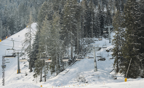 Chairlift at Italian ski area on snow covered Alps and pine trees