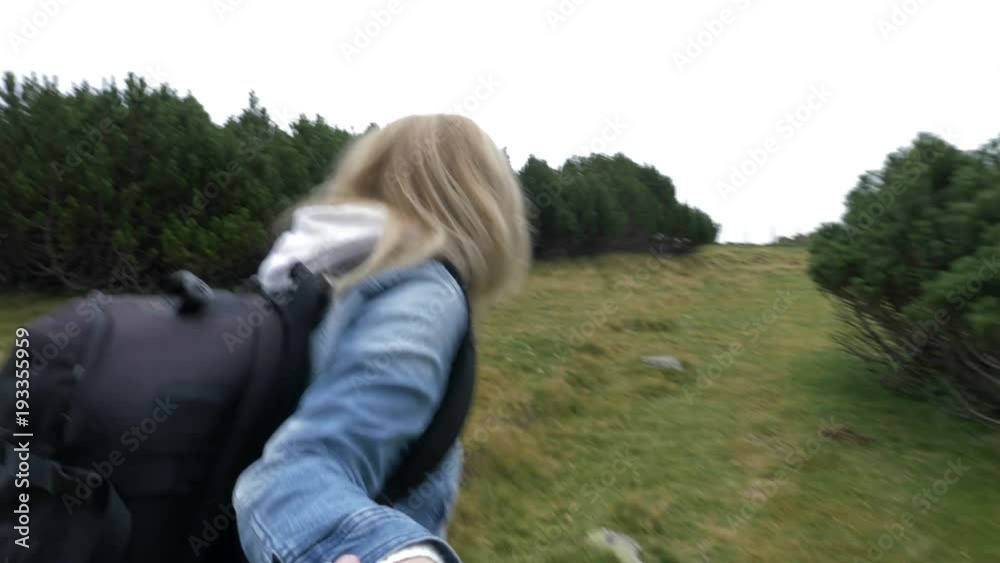 Smiling young woman in love holding hands and leading her boyfriend along alpine trees POV of highland trip concept Smiling young woman in love holding hands and leading her boyfriend along alpine trees POV of highland trip concept