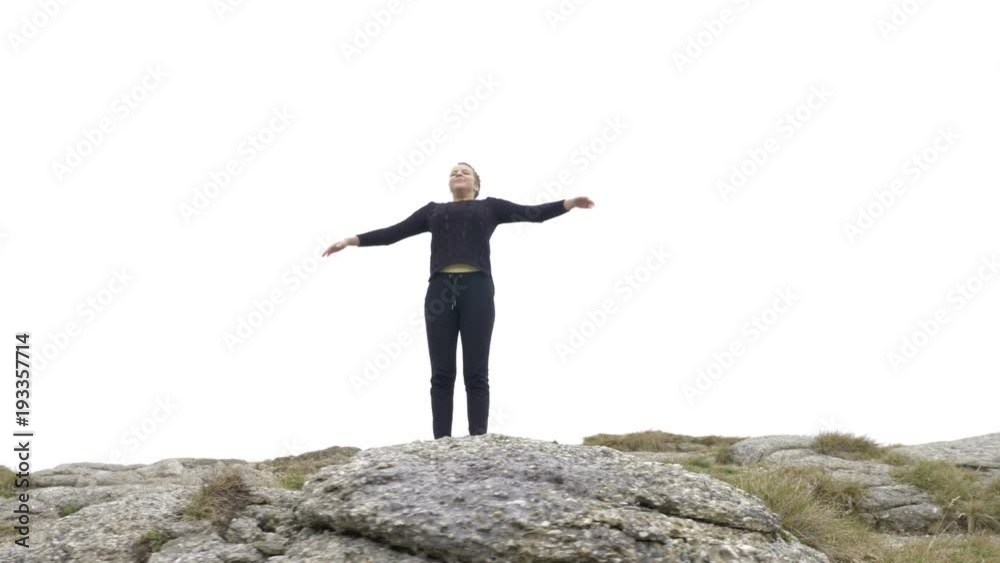 Pretty young lady doing yoga exercises on the mountain high raising arms while she taking a deep breath Pretty young lady doing yoga exercises on the mountain high raising arms while she taking a deep breath