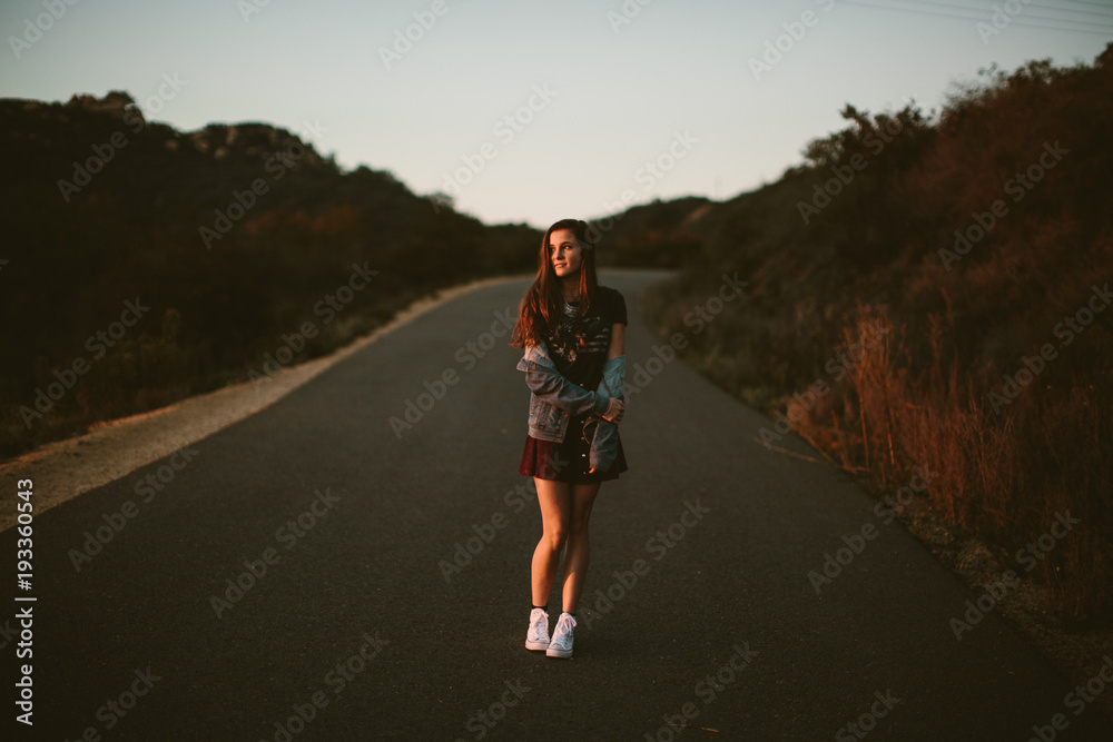 Dark portrait of a woman standing in road wearing a short skirt