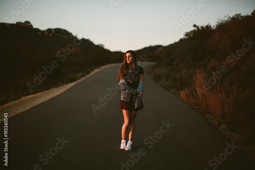 Dark portrait of a woman standing in road wearing a short skirt