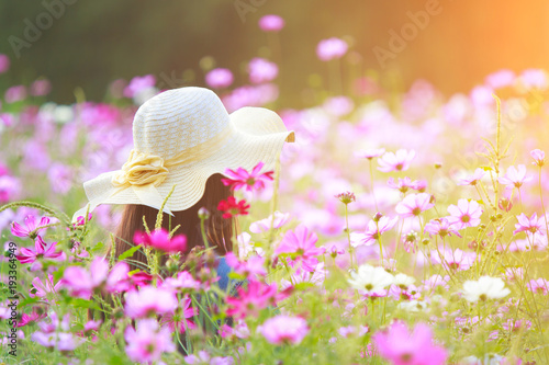 Fototapeta Naklejka Na Ścianę i Meble -  Woman wearing a hat in a field of flowers.
