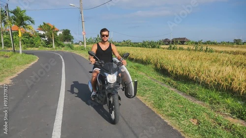 Man gonna surf spot on motorcycle with surfboard. Surfing lifestyle