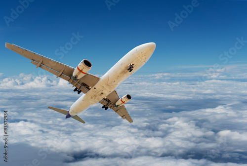 Commercial airplane flying above clouds and clear blue sky over beautiful scenery nature background concept business travel and transportation background.