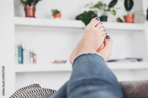 Woman's feet up on the coach against white wall. Beauty, fashion blogging , freelancer concept. Pedicure nail polish design. Copy space photo