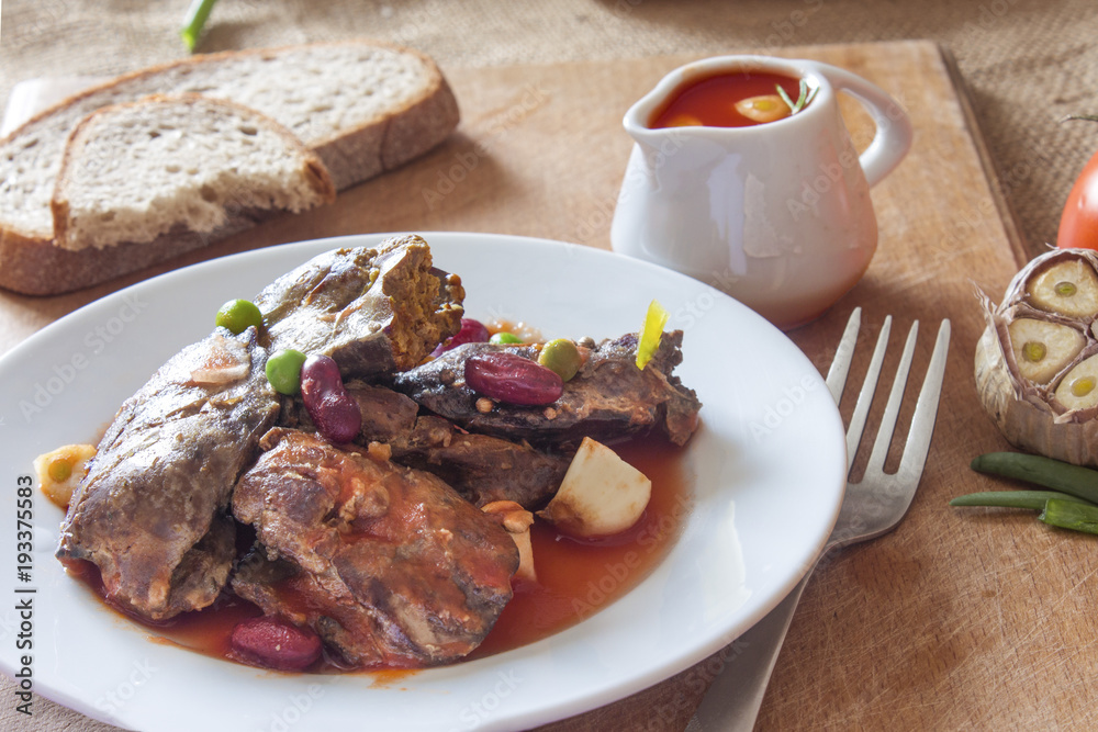 Moroccan dish of fried chicken hot liver in a plate with a spicy vegetable sauce on the table Moroccan dish of fried chicken hot liver in a plate with a spicy vegetable sauce on the table