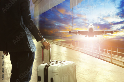 business man and traveling luggage in airport terminal building against jet plane flying over airport runway photo