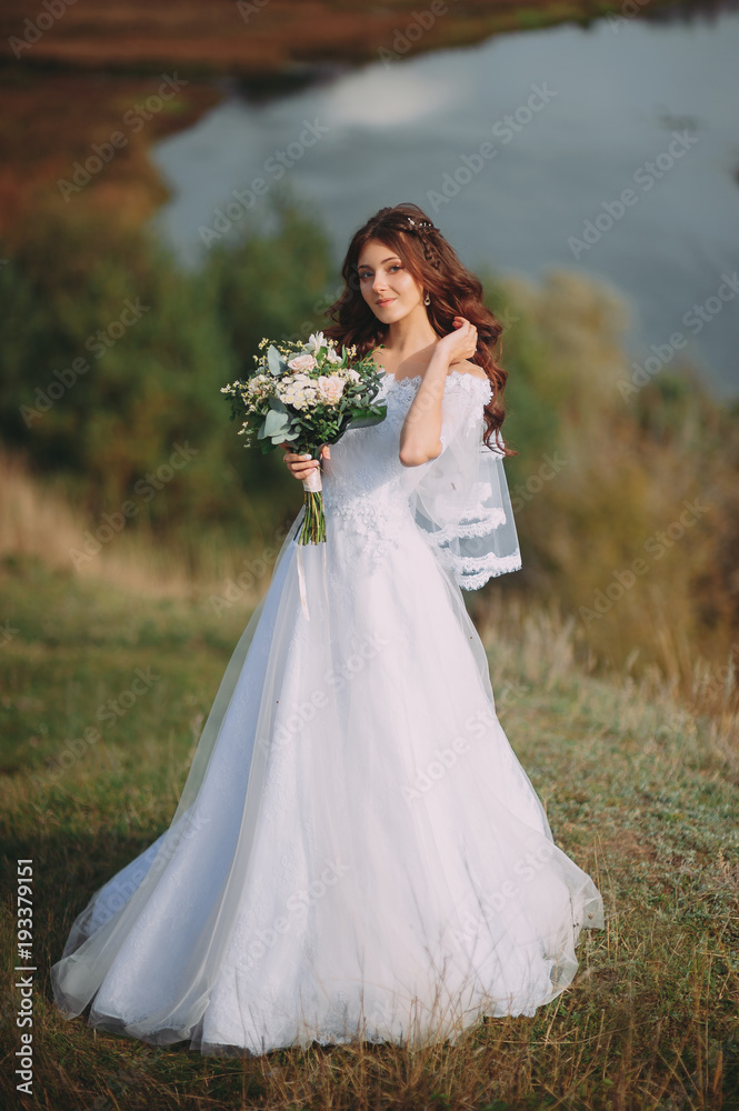 beautiful bride with stylish bouquet on the background of the lake