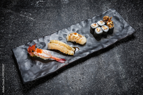  Japanese seafood sushi , roll and chopstick on a black plate