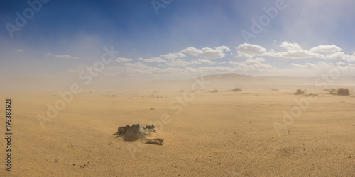Stone ring forms a fire pit in a vast sand desert under the cloud of a growing sandstorm.