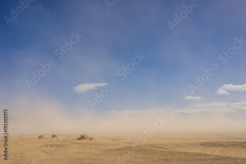 Szeroka piaszczysta pustynia w klimacie suszy objętym wietrzną burzą piaskową.