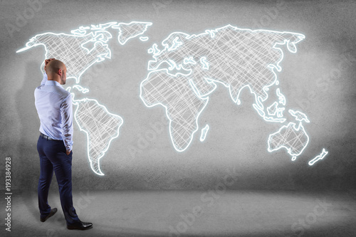 Businessman in front of a wall with a Hand drawn world map on a futuristic interface