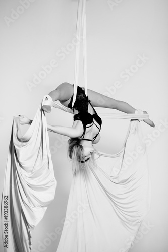 Beautiful aerialist girl doing acrobatic and flexible tricks on rwhite tissues photo