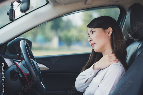 Asian businesswoman having pain on her shoulder and neck while driving