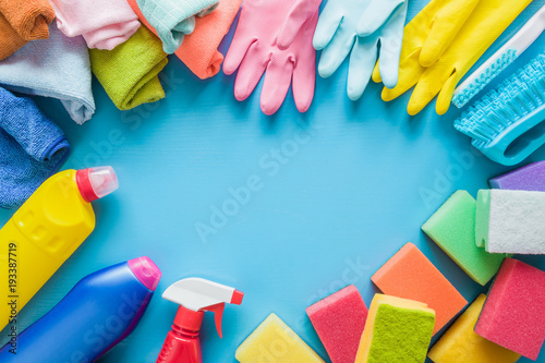 Colorful cleaning set for different surfaces in kitchen, bathroom and other rooms. Empty place for text or logo on blue background. Cleaning service concept. Early spring regular clean up. Top view.