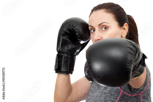 Active mature woman, fitness and boxing workout concept with attractive brunette female wearing fitness clothes and black boxing gloves, isolated on white with copy space and a clipping path