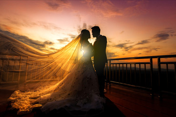 silhouette of wedding Couple in love kissing and holding hand together during sunset with evening sky background