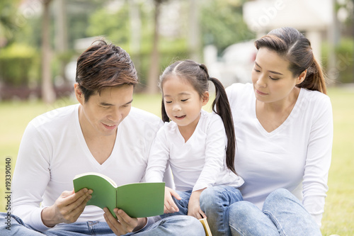 Asian family reading book together at outdoor place. People lifestyle concept.