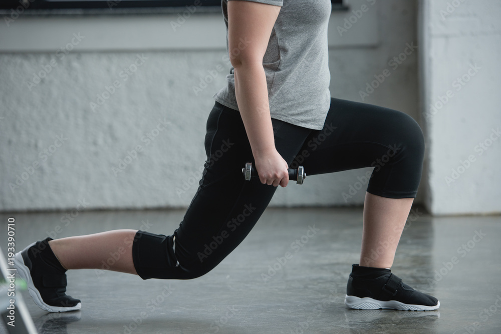 Curvy girl doing lunges with dumbbell in gym Curvy girl doing lunges with dumbbell in gym