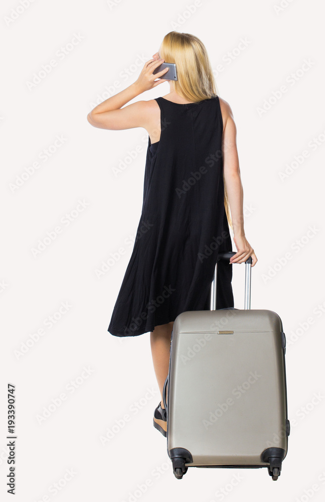 Back view of woman with suitcase talking on the phone. Back view of woman with suitcase talking on the phone.