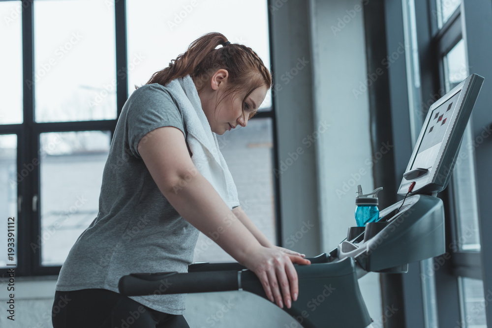 Obese girl resting on treadmill in gym Obese girl resting on treadmill in gym
